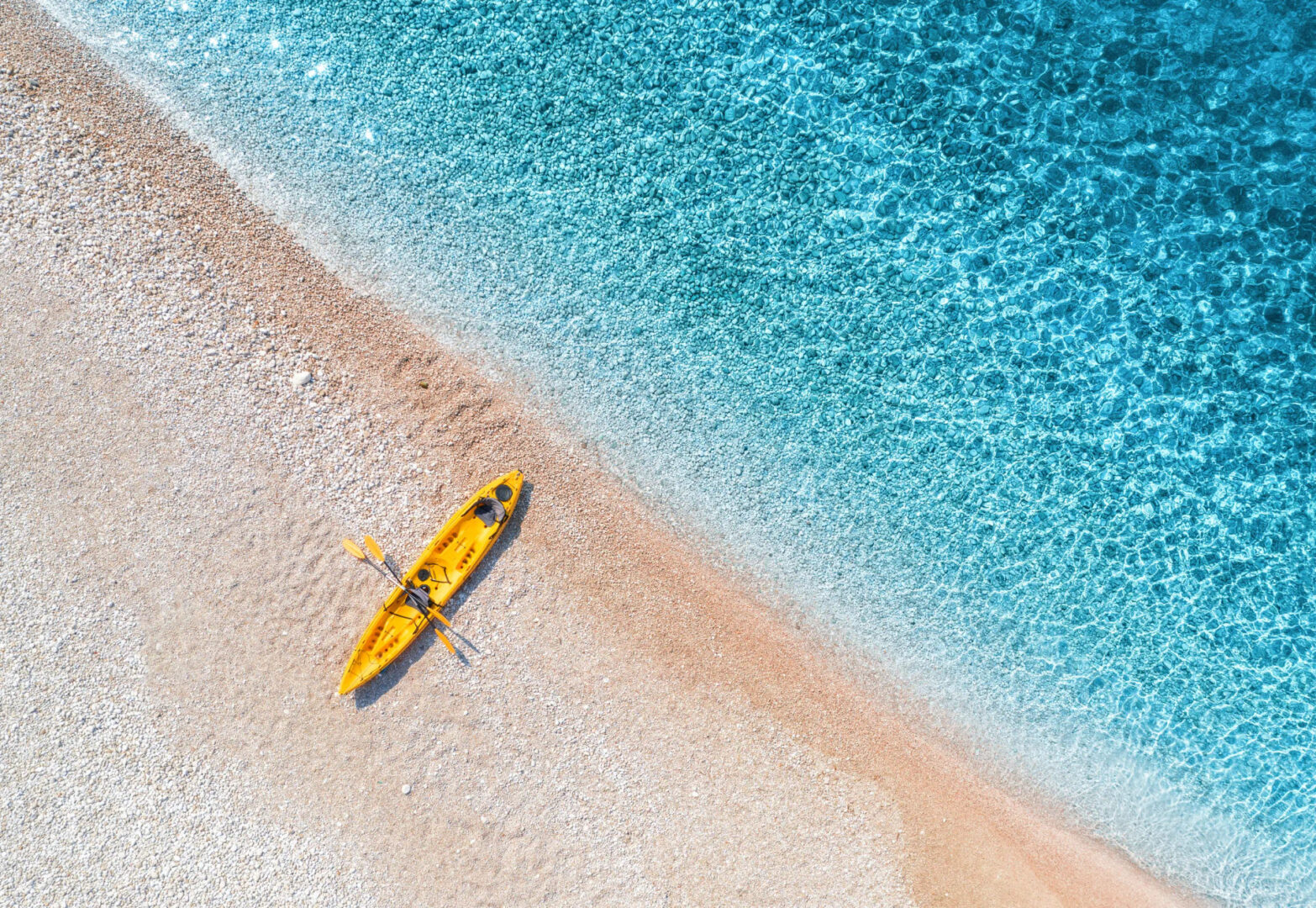 Aerial view of sandy beach with yellow canoe and blue sea, activities, Golden Yachting and Sailing.webp